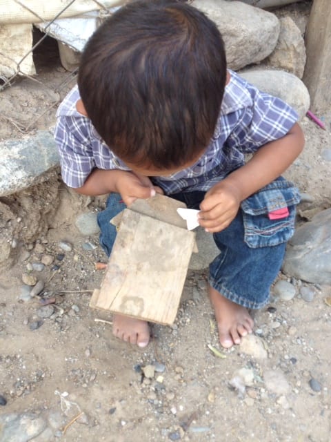 Young boy playing with his only toy... a paper bag